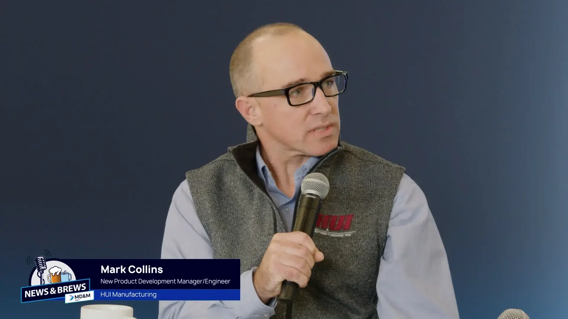 News and Brews logo in the corner with Mark Collins name over the top of a headshot of Mark Collins with a microphone in his hand